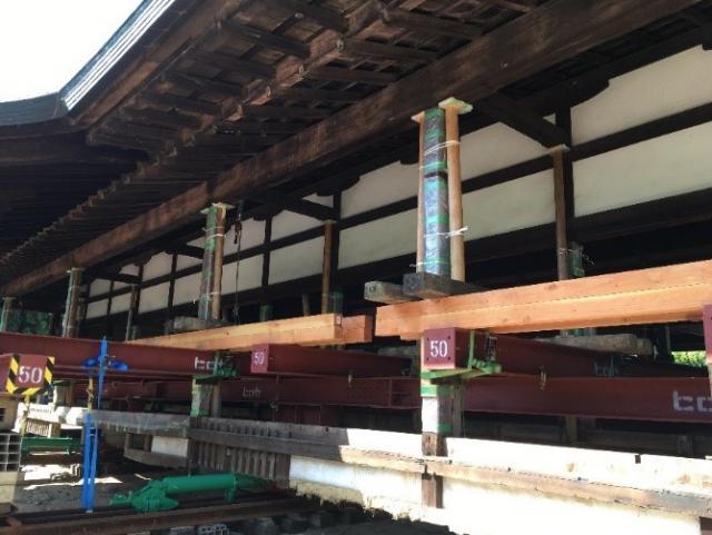 Photograph of an old wooden temple being renovated by new wood.