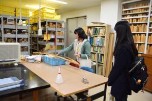 縄文時代遺跡より出土の弓のレプリカを前に