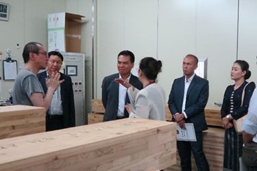 次世代建築実験棟内で実際に実施している試験内容について、CLT試験材を前にして、ラオス語に通訳しながら説明している様子
