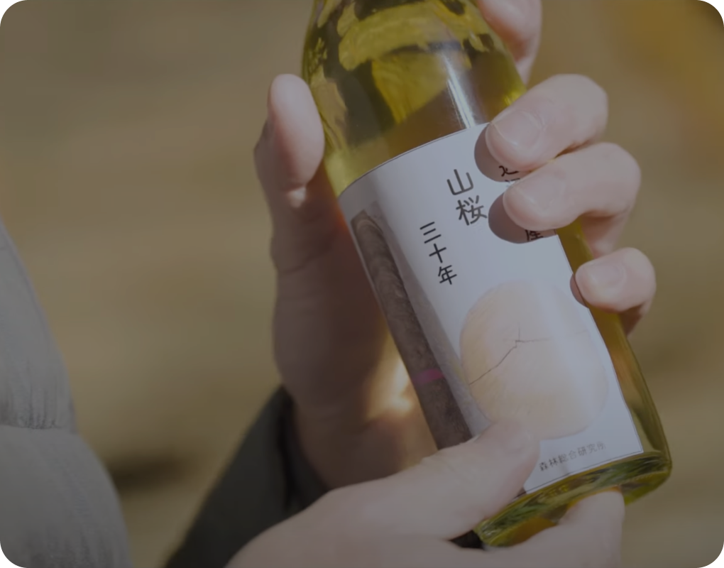 「木の酒」の瓶を手で握る写真