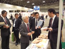 写真3 当所のブースで来場者の方々に説明する研究員