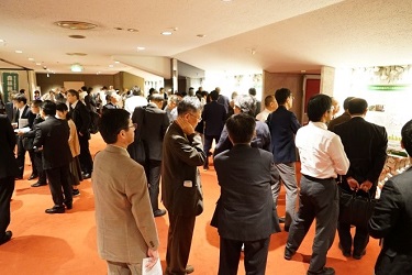 写真05:ポスター発表の会場にて担当者の解説に耳を傾けている様子
