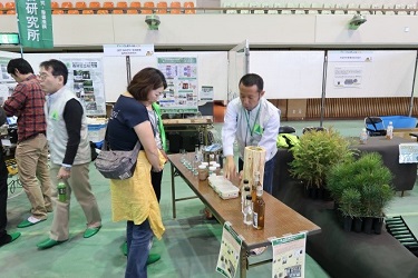 樹木の香りを豊富に含むアルコールを製造する技術開発の説明を聞いている様子