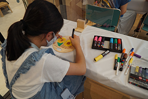 木のうちわに絵を描いて、オリジナルのうちわを作りを体験している様子