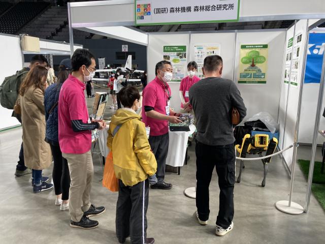 写真左、研究者が四足歩行ロボットについて解説している様子