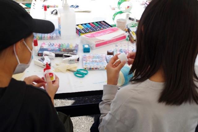 左側：経木で作ったパーツを土台に貼っているお子さん、右側：ランプの電源を入れているお子さんの写真