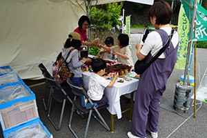 子供たちが木片と好みの球果を選んで楽しみながらオーナメントを作っている様子