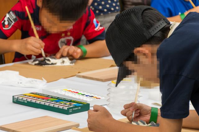 参加者の小学生が、クマの足型模型に好きな色を塗り、無中になっている様子。