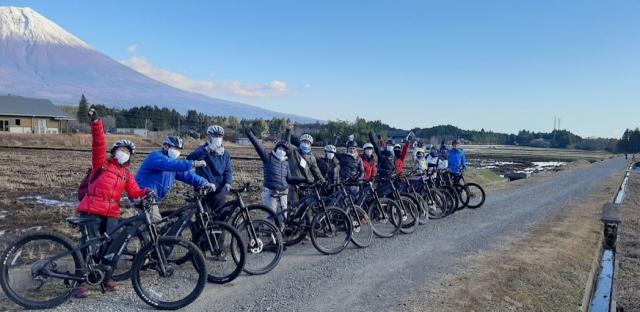 山のふもとでマウンテンバイクと共に記念写真におさまる人たち