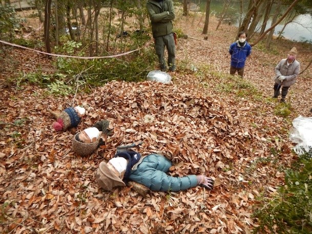 目を閉じて落ち葉のベッドに横たわる3人