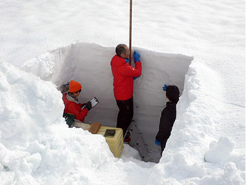 写真9：雪を掘って露出させた積雪断面を、研究者が調べている様子です。雪質や層構造を観測し、積雪の状態を把握しています。